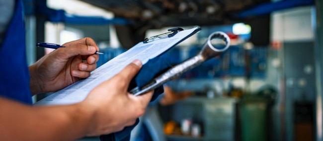 Mechanic-with-Clipboard-Inspecting-Vehicle Mechanic-with-Clipboard-Inspecting-Vehicle